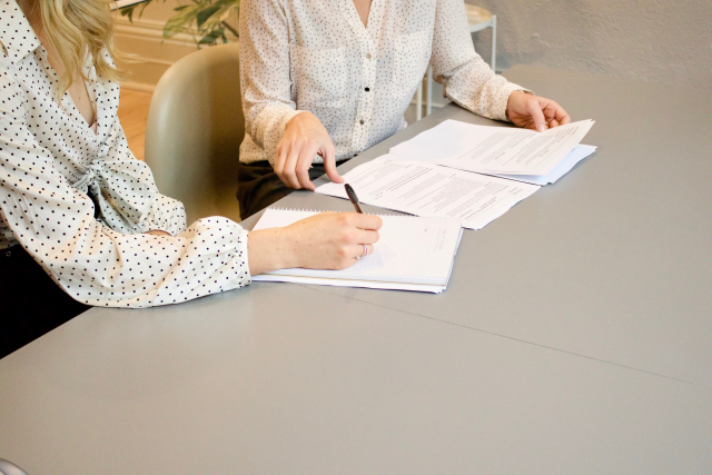 Two women look at documents on a table