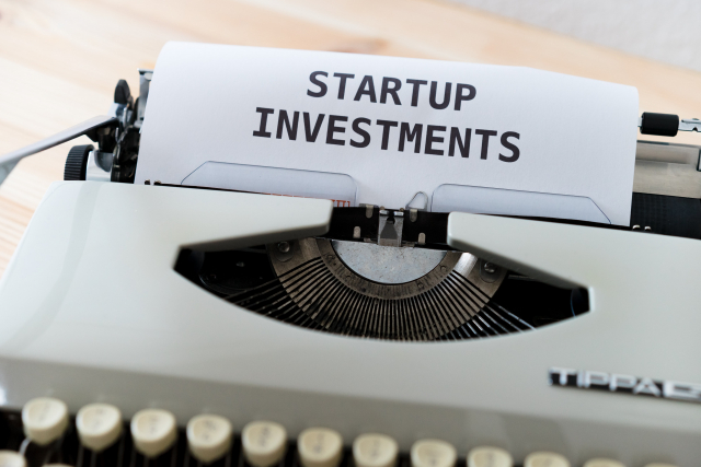 A grey typewriter and a paper with the worlds "Startup investments" printed on it