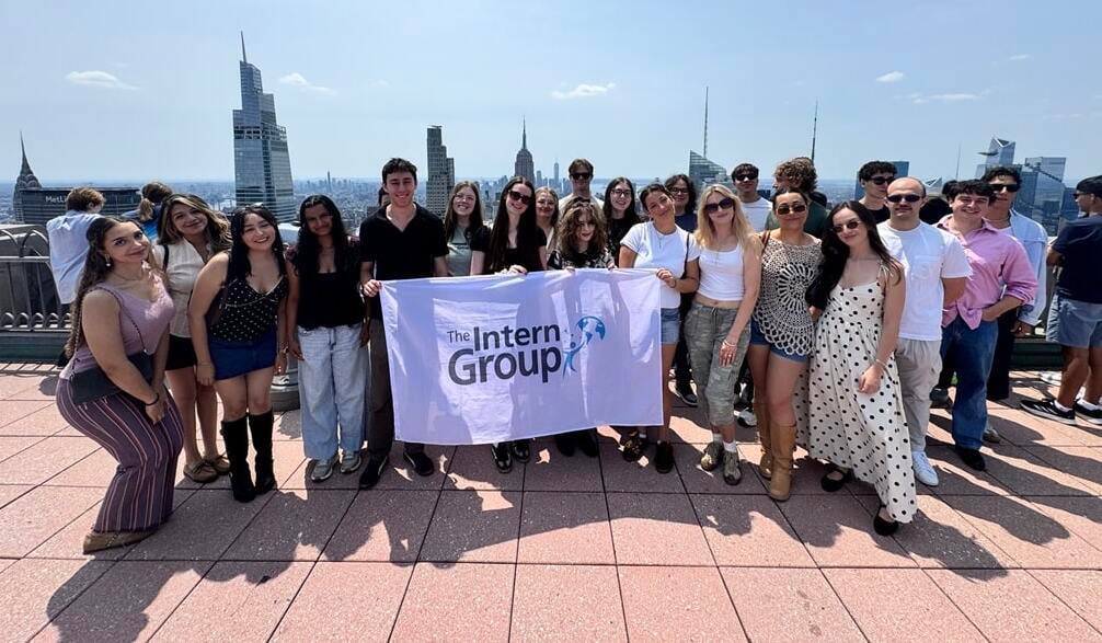 A group of interns in New York holding a The Intern Group flag