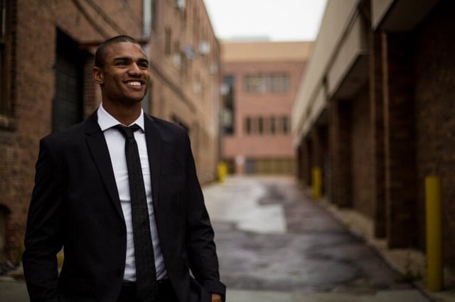 A man stands smiling in a suit.