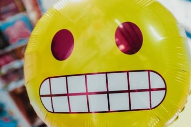 A large balloon printed to look like the grimacing emoji.