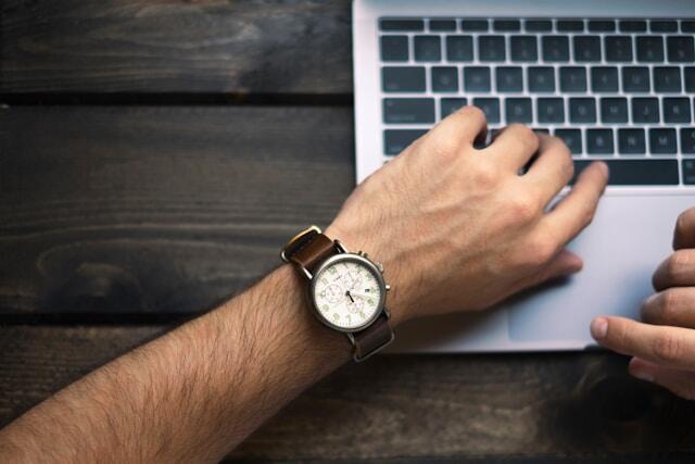 A man at the office looking at his watch as he works.