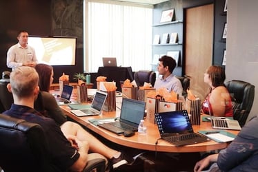 A confident business leader stands up and talks in a boardroom of employees.