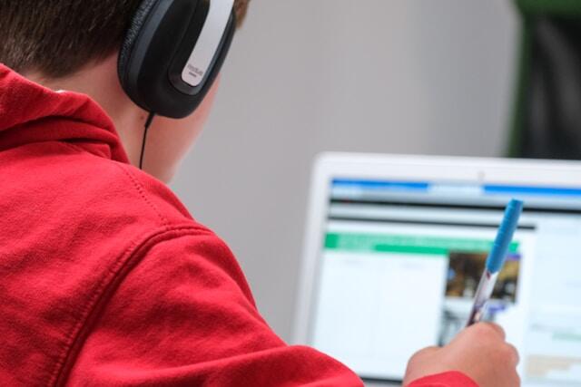 A student learning a second language with headphones and online study materials.