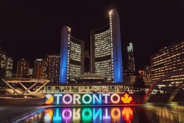 Toronto, Canada at night with 'Toronto' lit up in bright lights and reflecting in the water below.