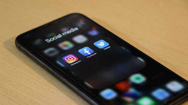 A black iphone shows social media apps
