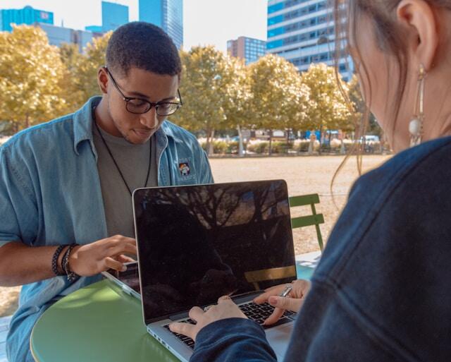 Gen Z workers working remotely outside a cafe.