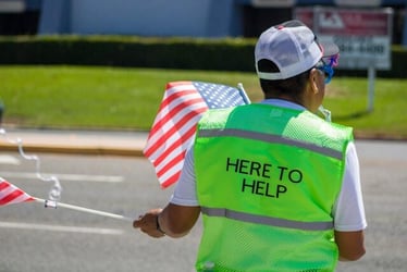 An NGO intern wearing a hi-vis jacket that reads 'here to help.'
