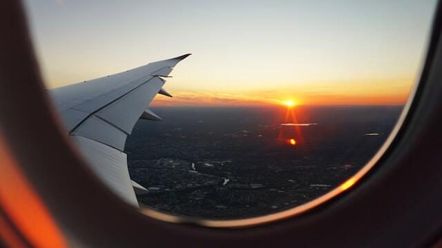 The view of a new city at sunset from a plane window, the airplane wing visible.
