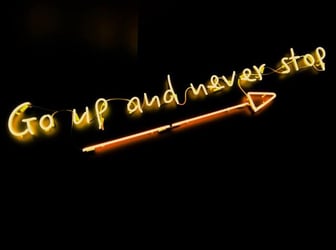 A neon sign that says 'go up and never stop.'