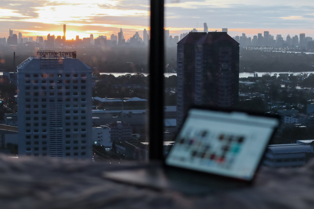 A laptop sits on a table near a window with a city view