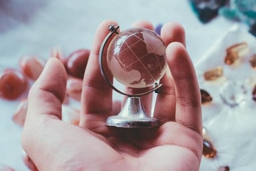 Somebody holding a miniature globe in their hand.