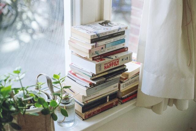 A stack of books on a windowsill.