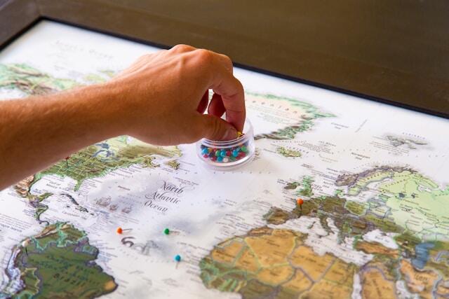 A young professional puts pins in a world map showing where's traveled to.