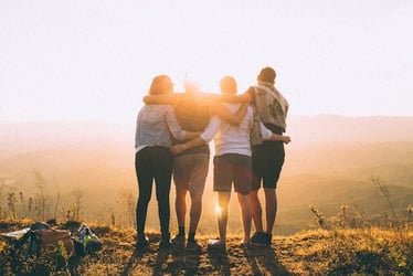 Friends made abroad hugging at sunset after a hiking trip.