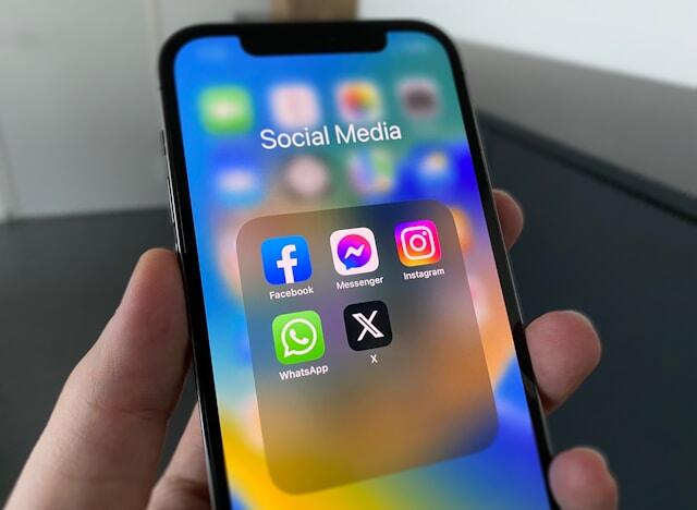 A mobile phone showing common social media apps like Facebook, Instagram, and X.