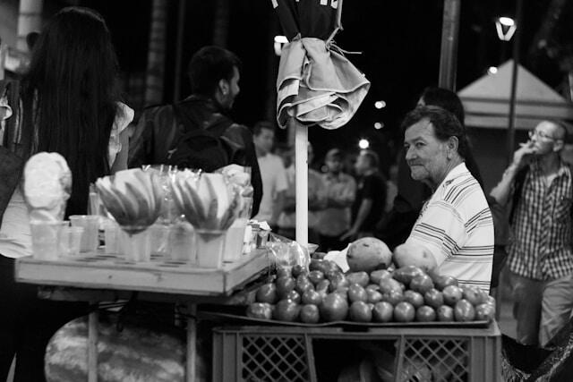 A black and white photo of a man at a food market stall in Medellin, Colombia