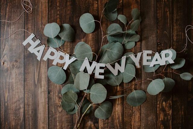 Eucalyptus on a wood table with bunting over the top that reads 'Happy New Year'.