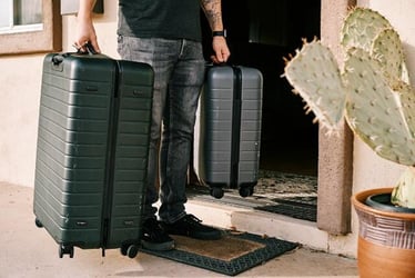 A young professional carrying two suitcases.