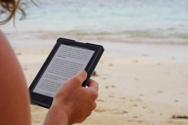 A professional reading a Kindle at the beach during their internship abroad.