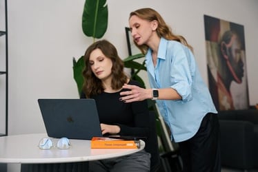 A difficult coworker leaning over a colleague and staring at their work.