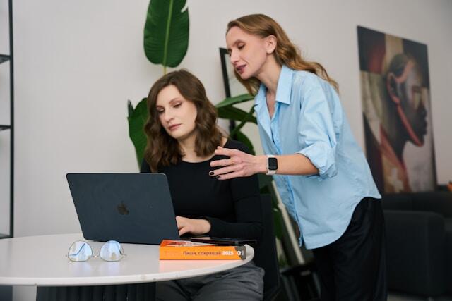 A difficult coworker leaning over a colleague and staring at their work.