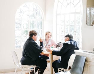 Friends formed at an internship abroad sit around a table together, laughing.