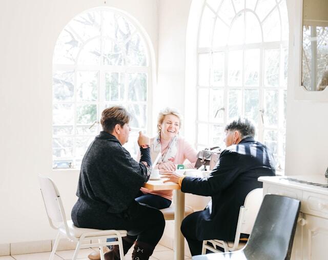 Friends formed at an internship abroad sit around a table together, laughing.