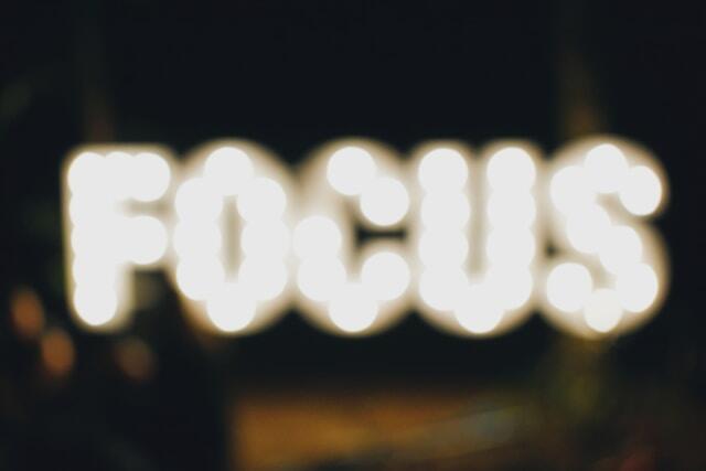 An out of focus neon sign that reads 'focus'