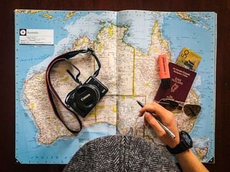 A map of Australia with a passport and camera on top.