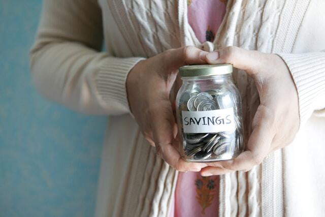 A young professional holding a jar of savings for their time abroad.