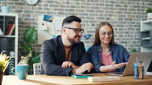 Two young professionals collaborate together on a work project at a desk.