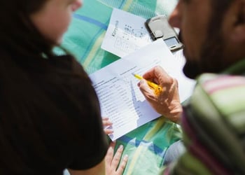 A man teaches a girl a new language by using a foreign language vocabulary sheet.