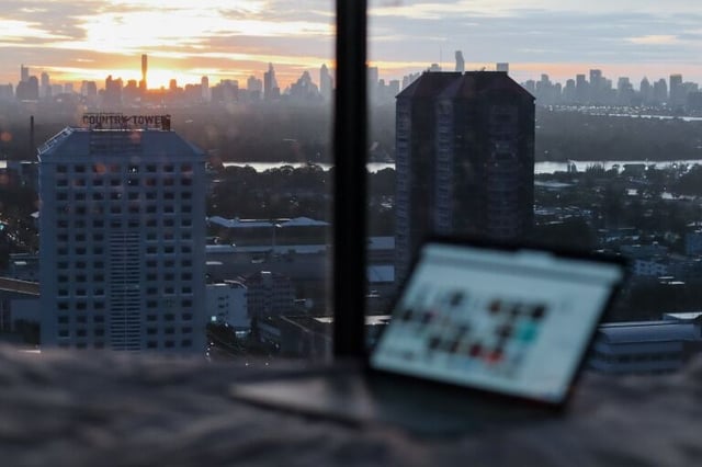 A laptop sits on a table near a window with a city view