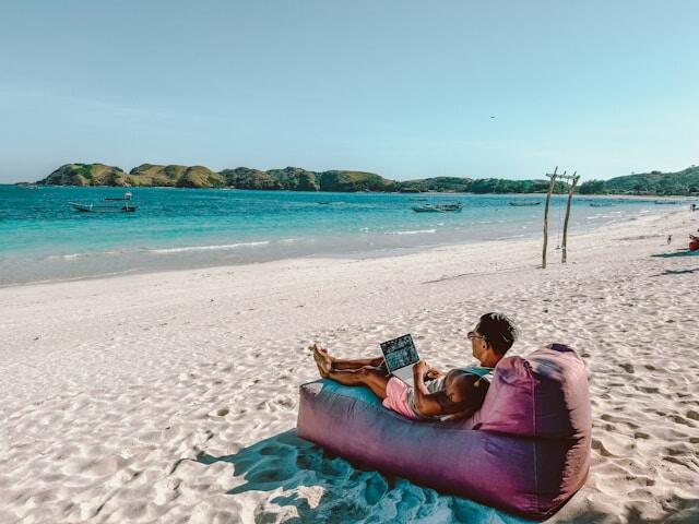 A man working on a laptop on a beach.