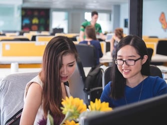 Two professional young women collaborate and work together in an office.