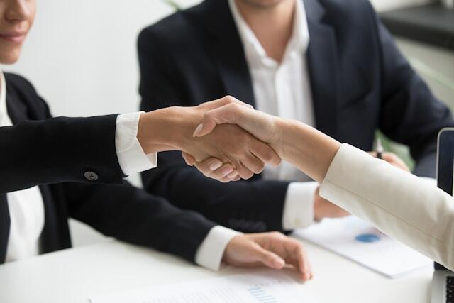 Two people in business clothing shake hands.