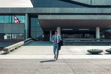 A man in a business suit exits an office building.