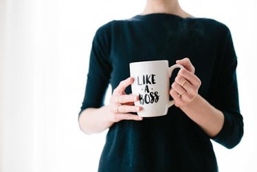 A woman holding a mug which says 'like a boss.'