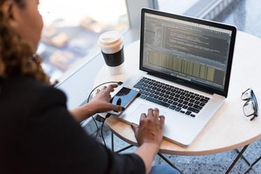 A young female entrepreneur writes and edits code on her laptop.