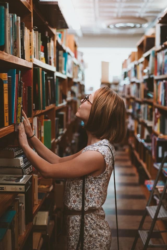 A young woman searches for a book in a library