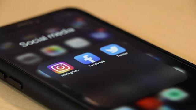 A close up of a phone displaying the app icons for Instagram, Facebook, and Twitter