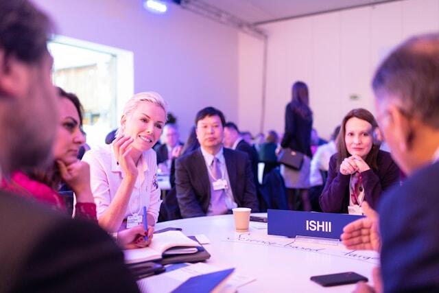 Professionals sit around a table, talking, at a networking event.