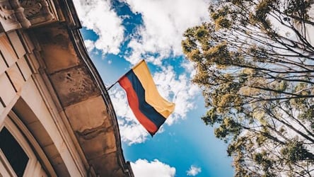 The flag of Colombia flying in the sky above a building