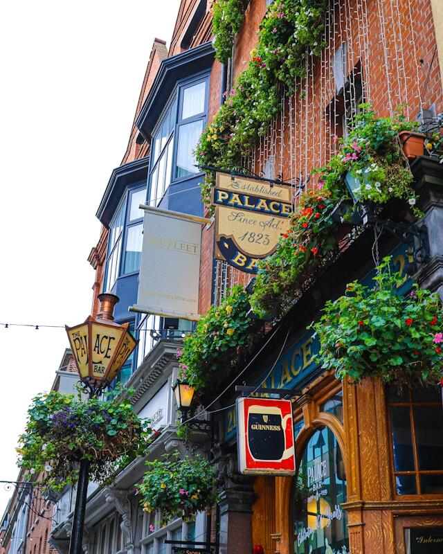 An old-fashioned, traditional pub in Dublin with flowers outside and Guinness sign.