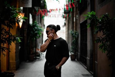 A young man stands facing to the side, exploring a street in Spain.