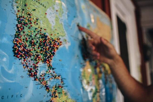 Someone points to a world map which includes pins for every location they've been to.