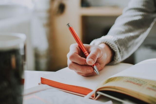 A close up of a hand writing in a notebook as they learn a new language.