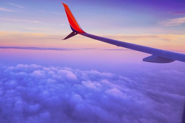 The view from a plane window as it flies through clouds, the wing visible to one side.