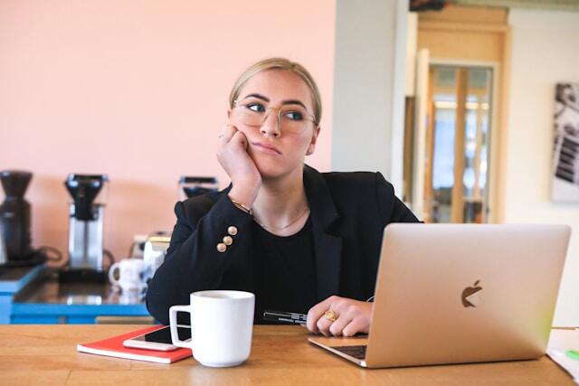 A young professional woman looks bored at her desk as she wonders if she made the right career choice.